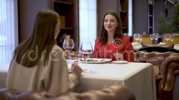 一个服务员给两个坐在餐厅一张桌子上的女孩带来一道美味的菜两个女朋友心情好休息视频的预览图