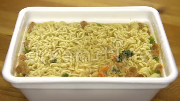 方便面和中国筷子混合在一起在一个特殊的塑料板上酿造黄色拉面视频的预览图