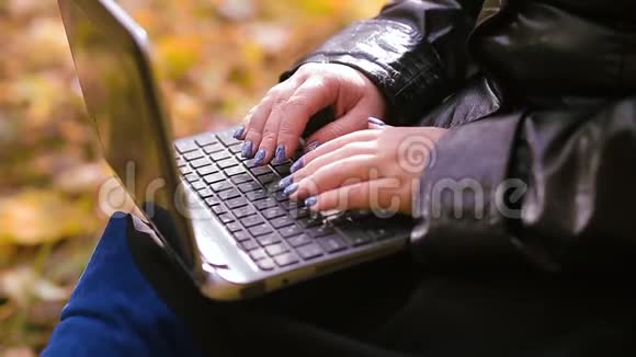 在秋叶模糊的背景下女性的手在电脑键盘上打字视频的预览图