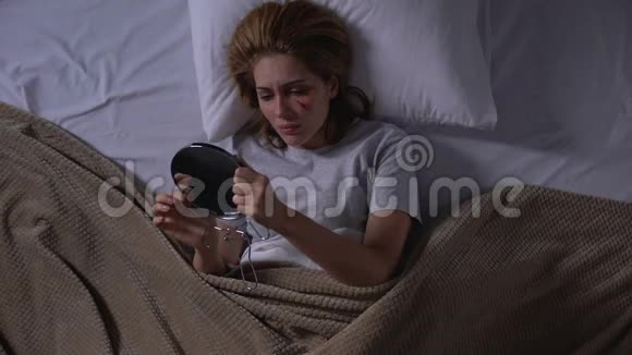哭泣的女性用粉底照镜子覆盖面部伤口躺在床上视频的预览图