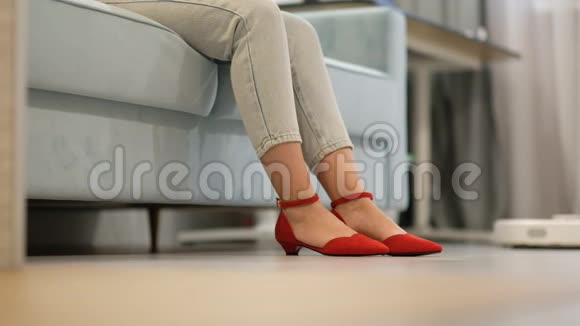 机器人吸尘器一个电子吸尘器骑在一个女人的脚下穿红鞋的女人正在休息视频的预览图