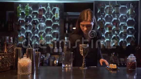 一个长着棕色长发的巴门女孩把许多冰块放进一个杯子里把一大块冰块放进一个金属碗里视频的预览图