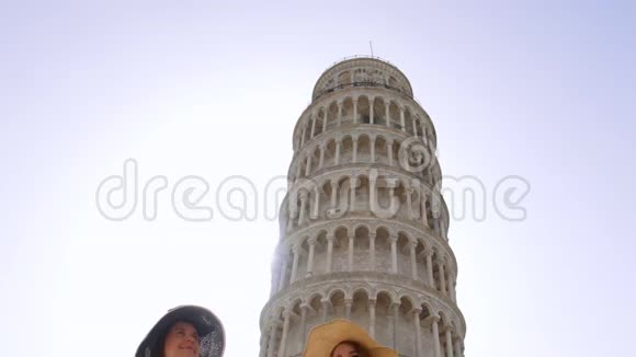意大利比萨两个穿着睡衣的年轻女人在比萨斜塔边散步欣赏风景视频的预览图