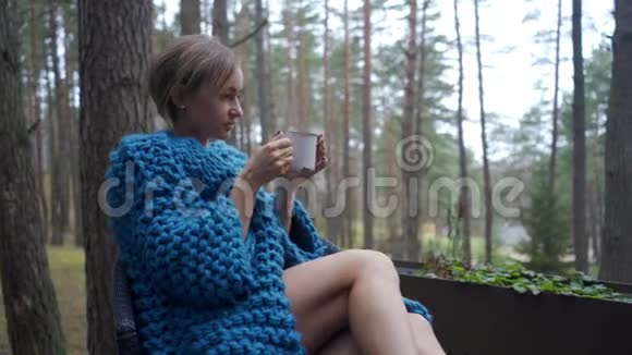 有魅力的女孩在睡衣坐在阳台上喝杯茶或咖啡享受自然视频的预览图