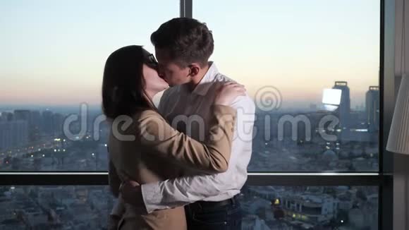夫妇男人和女人在全景窗口附近跳舞和亲吻城市景色视频的预览图
