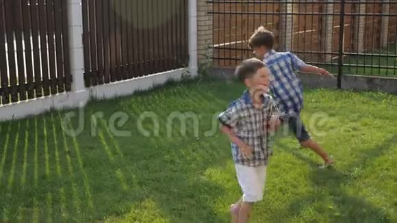 微笑的小男孩笑着沿着绿色的院子草坪奔跑视频的预览图