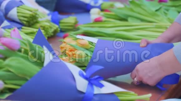 女花匠用包装工艺纸包裹着美丽的郁金香花束视频的预览图