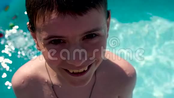 男孩站在游泳池的楼梯上微笑着掉进水里视频的预览图