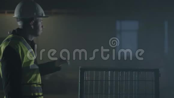 穿着建筑工服和头盔的严肃男子走过来把手放在笼子上环顾废弃的建筑周围视频的预览图