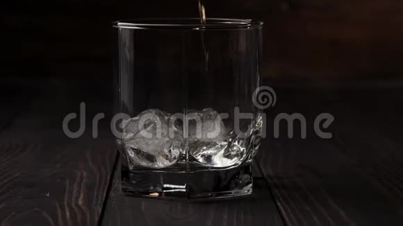 豪华威士忌手把金色的威士忌从一个方形的瓶子里倒入一个玻璃杯里桌子上放着真正的冷冰视频的预览图