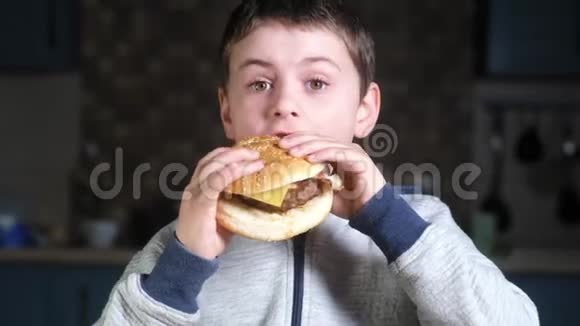一个饥饿的男孩咬了一个大汉堡嘴里塞满了食物笑起来视频的预览图