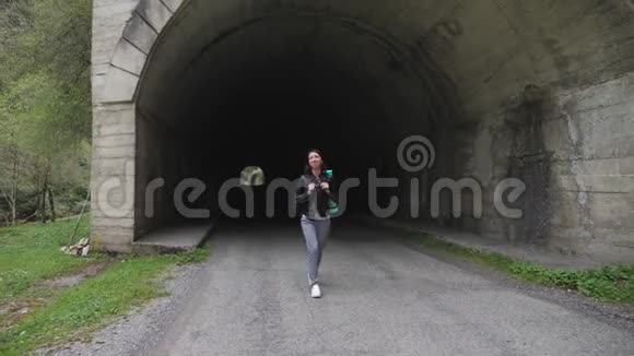 带着背包的旅行者女人独自走在路边的隧道里视频的预览图