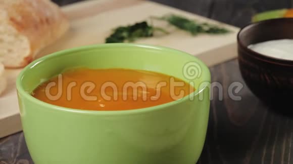 奶油南瓜汤烹饪厨师把奶油南瓜汤放在装饰好的木桌上的绿色碗里快关门4K视频的预览图