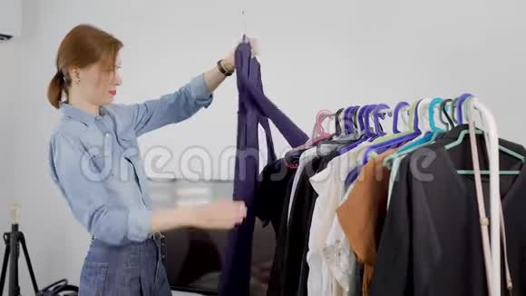漂亮的红发女人在家里看着挂在衣架上的蓝色连衣裙脱下它独自整理衣柜视频的预览图