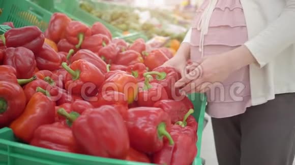年轻孕妇在蔬菜店里选择红辣椒视频的预览图