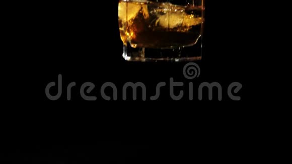豪华威士忌手把一杯带冰块的金色威士忌放在黑色的桌子上背景是黑色的视频的预览图