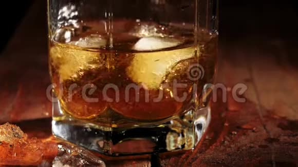 豪华威士忌冰浮在棕色的木桌上在一杯金色威士忌中旋转不倒翁威士忌波旁酒视频的预览图