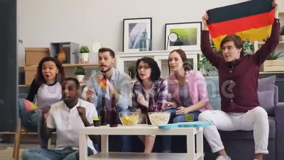 快乐的德国人在家看体育节目举着旗子玩视频的预览图
