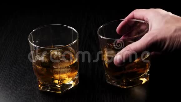 豪华威士忌手拿一杯带冰块的金色威士忌再拿一杯叮当作响准备喝酒视频的预览图