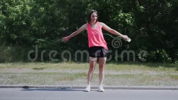 年轻活泼的女孩跳舞背包孩子在公园跳舞可爱的女孩戴着耳机在公园里表演牙线舞可爱的女孩哈视频的预览图