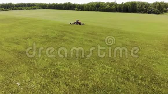 拖拉机把新鲜的青草割成青贮饲料和牧草用作农场的动物饲料视频的预览图