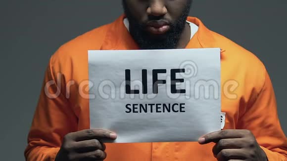 非裔美国危险囚犯手中纸板上的无期徒刑短语视频的预览图