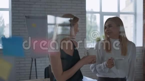 两个成功的快乐商业伙伴在办公室的午休时间交流和欢笑女人喝咖啡视频的预览图