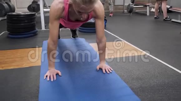 美丽的运动型肌肉女性金发在健身房锻炼健身女性做俯卧撑视频的预览图