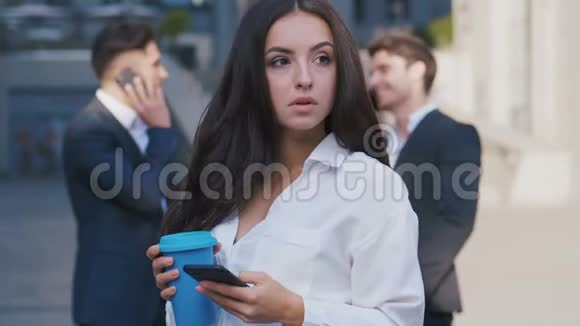 美丽的年轻女性女商人在商业区街道上用智能手机打破户外的画像视频的预览图
