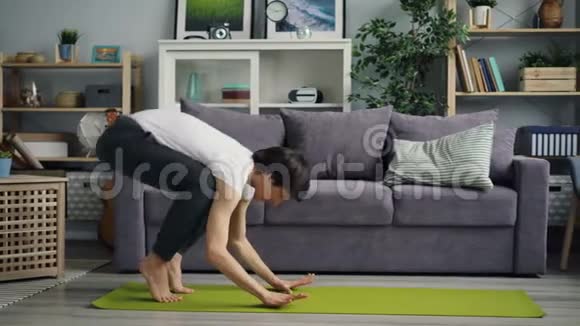 一个英俊的亚洲人独自在家做瑜伽练习时倒立视频的预览图