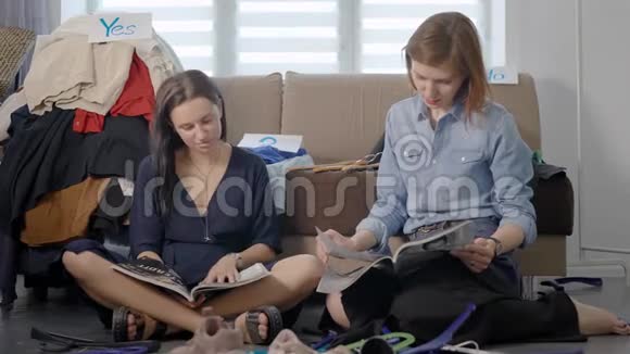 两个女朋友坐在客厅的地板上看杂志翻页聊天视频的预览图