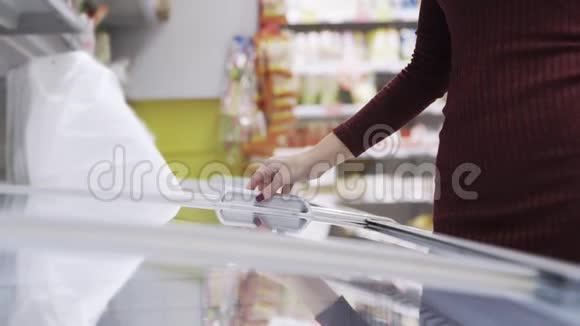 女人打开冰箱在超市里寻找冷冻食品并把它关上视频的预览图