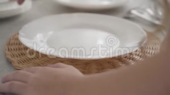 特写高加索女性的手在桌上端盘子勤快的孩子把餐具放在盘子杯垫上视频的预览图