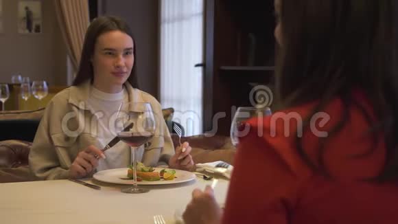 两个积极的女朋友坐在现代餐厅里在一起聊天的女孩在谈话视频的预览图