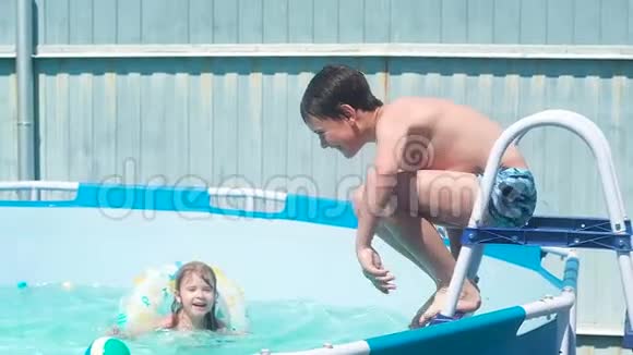 男孩从楼梯跳到游泳池在那里小女孩在一个充气里游泳视频的预览图