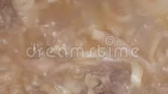 烹饪食物特写镜头洋葱块肉用煮沸的油在大锅里炖搅拌原料视频的预览图