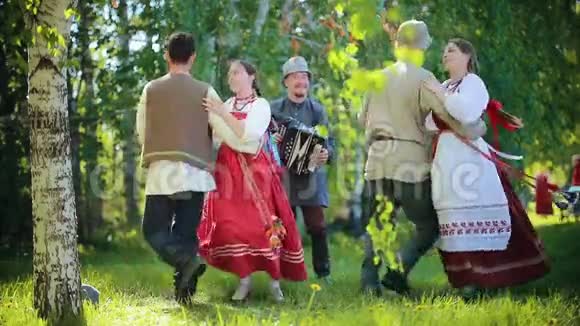 两对穿着俄罗斯服装的夫妇用手风琴在田野上跳舞视频的预览图