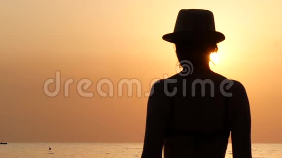 海边戴帽子的年轻女子的剪影视频的预览图