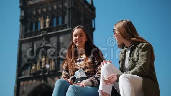 两个女人坐在查尔斯桥塔的背景上谈笑风生视频的预览图