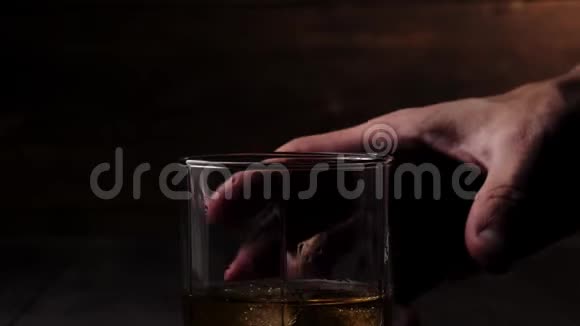 豪华威士忌手拿着一杯金色威士忌和真正的冷冰从桌子上的木制背景视频的预览图
