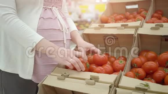 超市商店里选择西红柿的孕妇视频的预览图