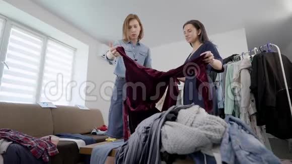 年轻的黑发女郎和她的发型师正在检查和整理家里的衣柜视频的预览图