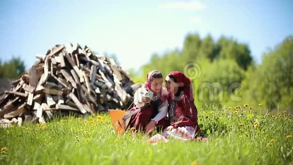 两个穿着俄罗斯传统服装的年轻女人坐在田野上自拍视频的预览图