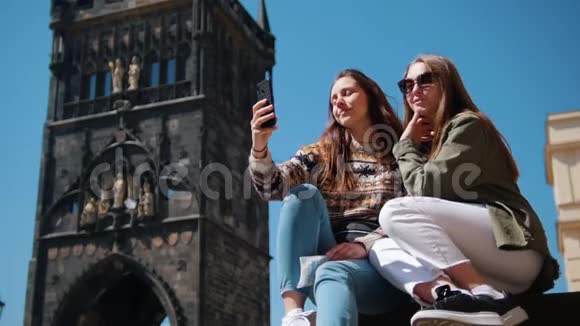 两个女人坐在查尔斯桥塔的背景上自拍他们的朋友来找他们视频的预览图