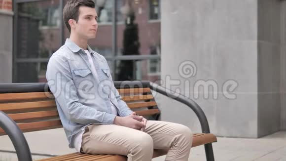 坐在长椅上等待年轻人检查时间视频的预览图