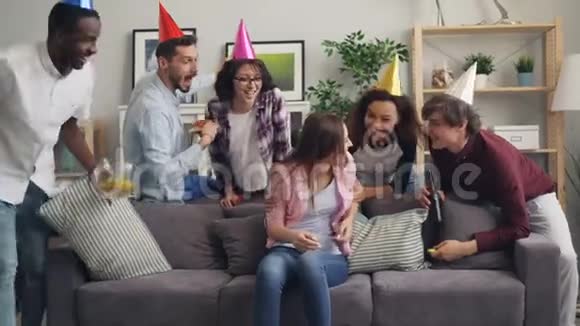笑着戴着派对帽的朋友祝贺女孩生日吃薯片视频的预览图