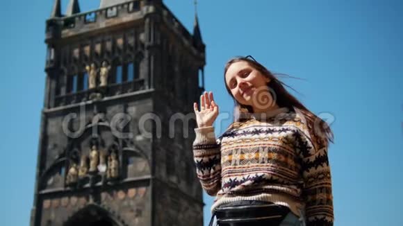 一位年轻女子站在查尔斯桥塔的背景上她的手在挥视频的预览图