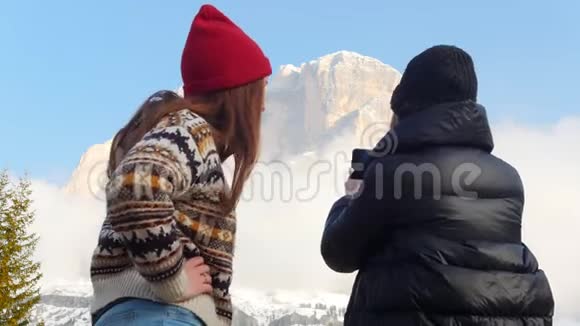两个年轻的旅行妇女站在山前拍了一张照片视频的预览图