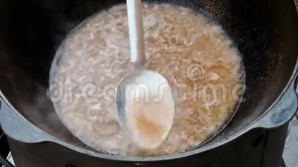 一块块带洋葱的肉用大锅里的煮沸的汤汁煮厨师把热油倒进锅壁视频的预览图