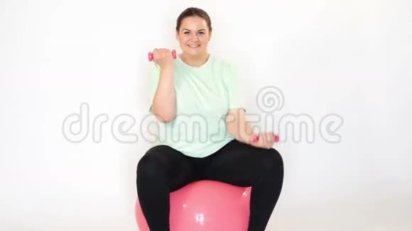 胖女人在健身球上用哑铃做运动视频的预览图